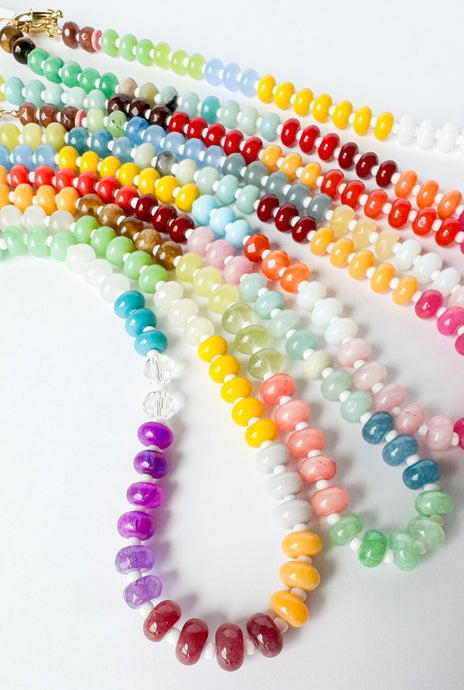 Colorful beaded necklaces with white seed beads on a white background